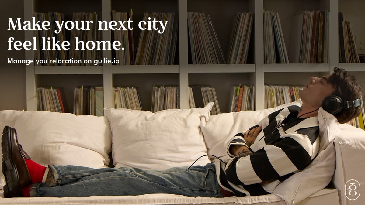 A man lying on a sofa with headphones on in front of shelves of records, with the headline Make your next city feel like home